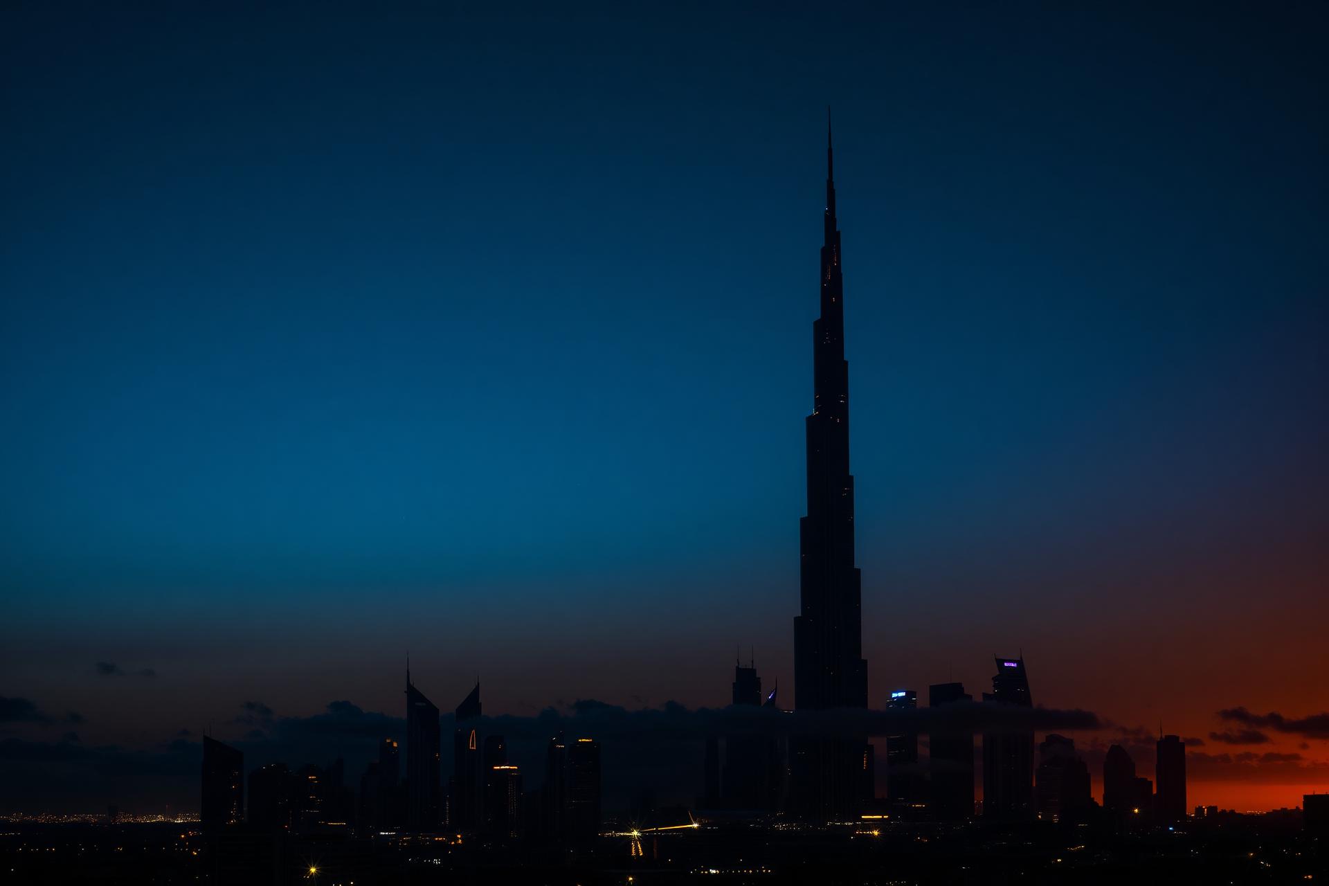 Dubai skyline at dusk featuring the Burj Khalifa silhouetted against a golden horizon